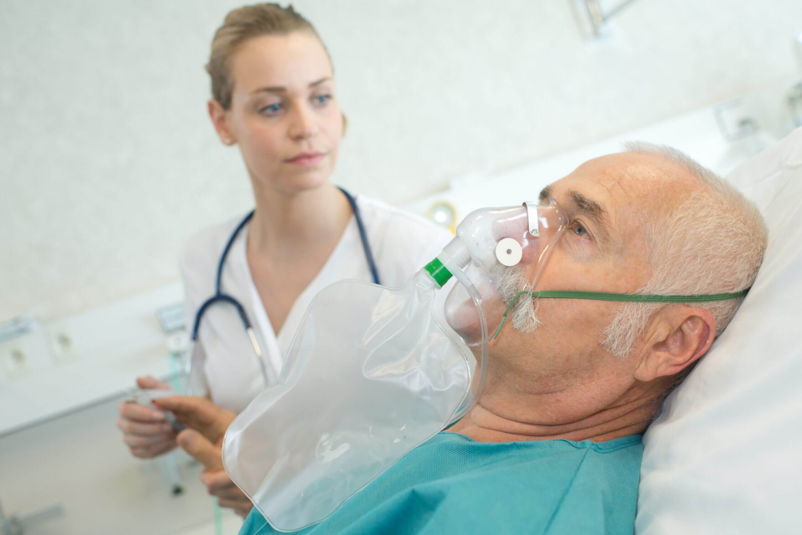 Nahaufnahme eines älteren Mannes, der mit einer Krankenschwester eine Sauerstoffmaske verwendet