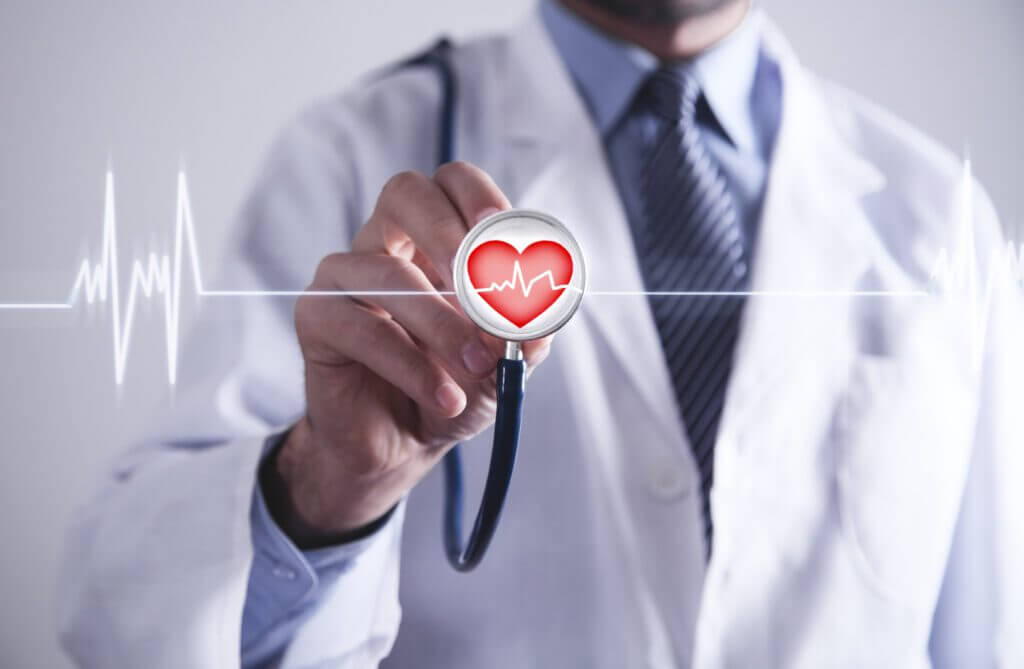 Arzt mit Stethoskop hält rotes Herz