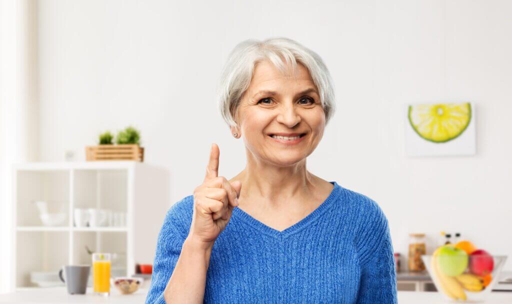 femme âgée souriante pointant le doigt vers le haut